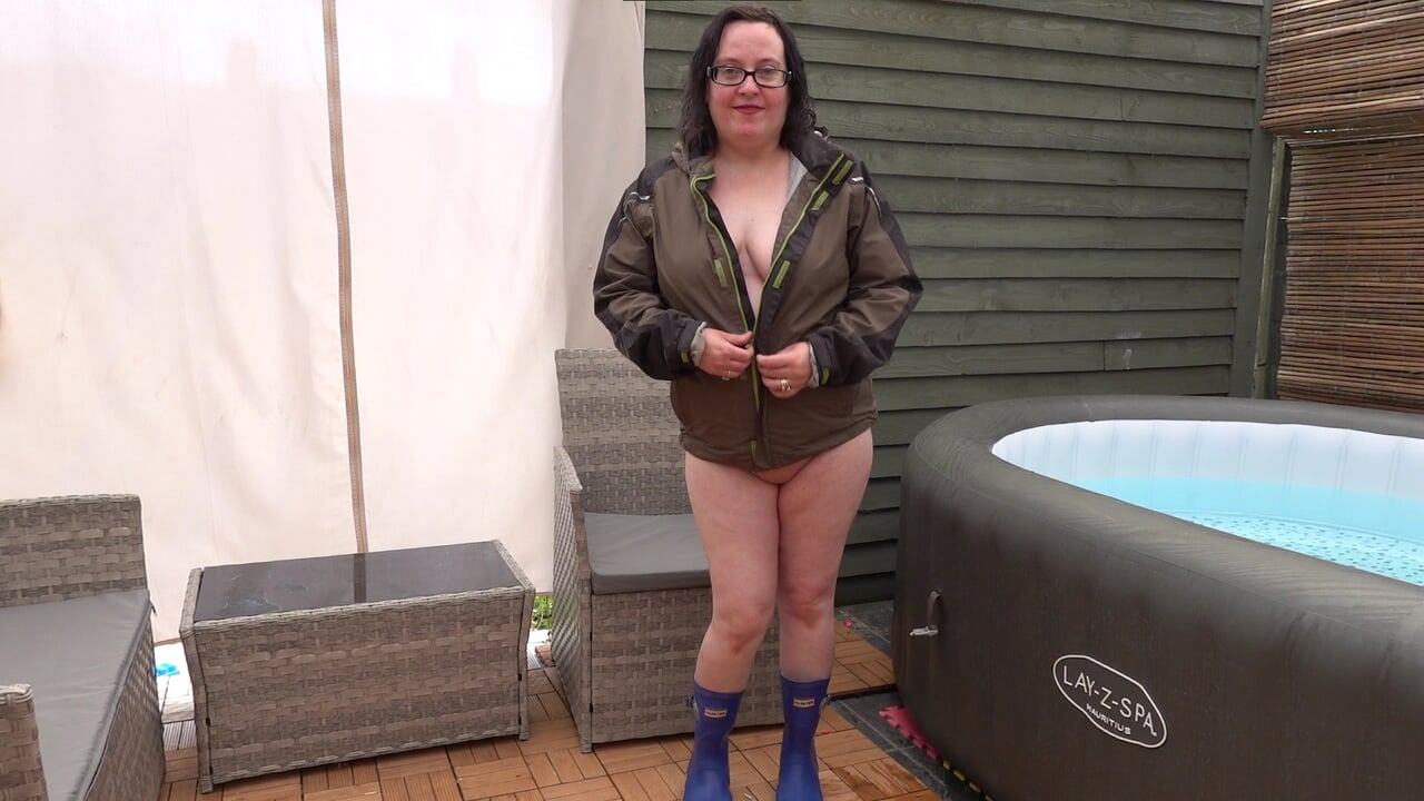 Sexy wife posing in Wellingtons and coat playing with big breasts