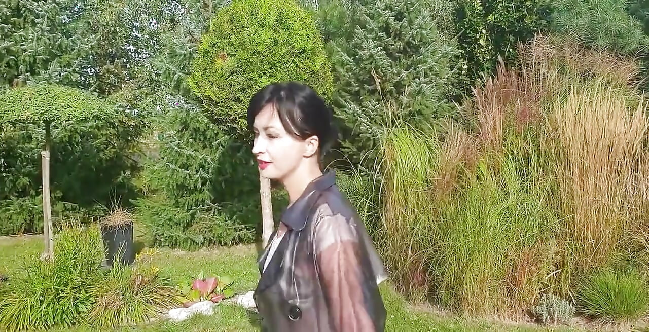 Garden, beautiful sunny day. Wanilianna in transparent raincoat, black seamed nylons